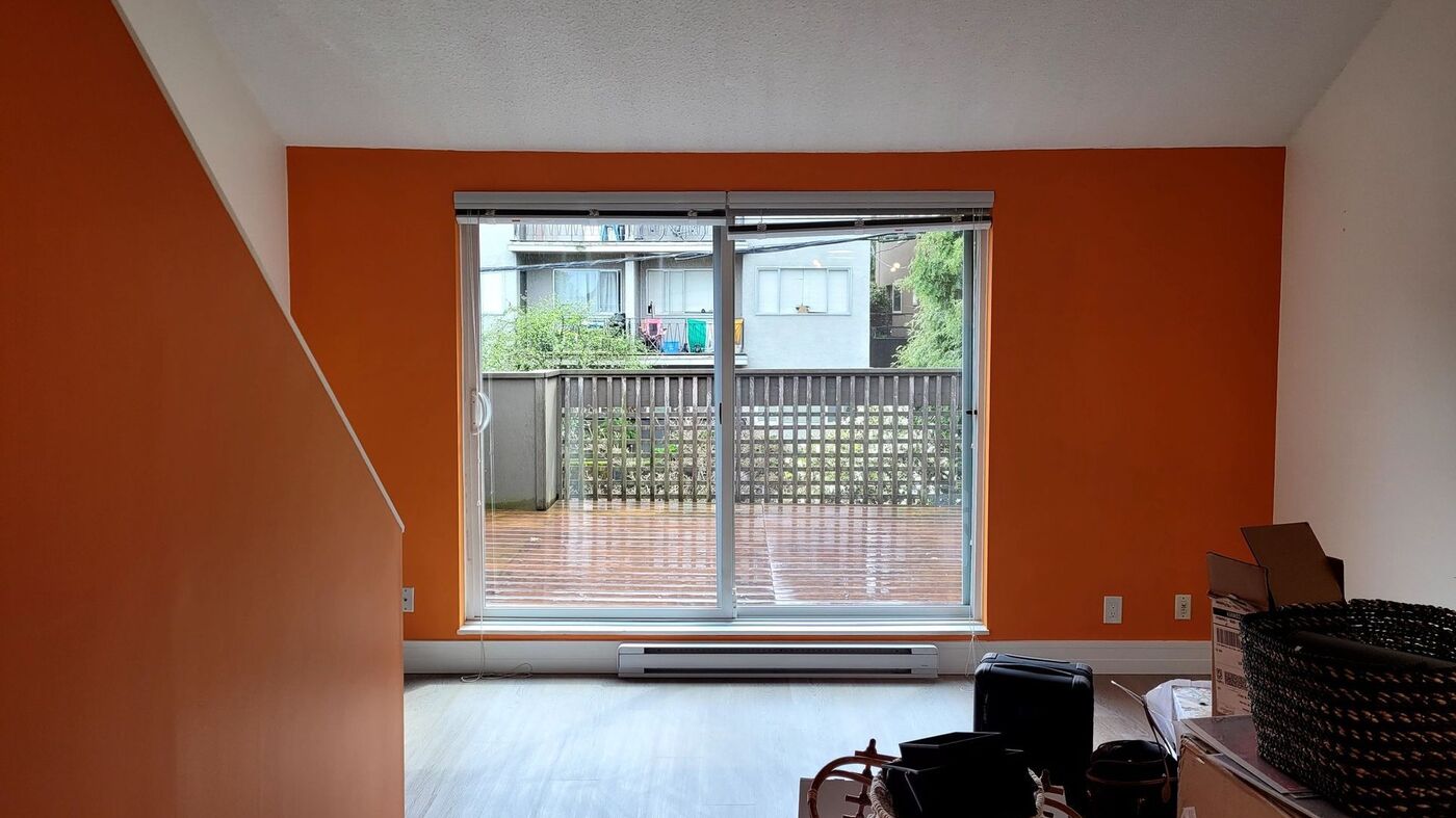 Interior of a Vancouver condominium painted by Davor's Painting with a saturated orange accent wall against white trim and a sliding patio door.